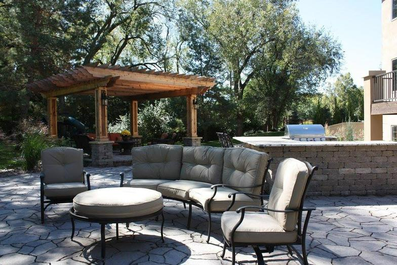 a patio with a couch and chairs under a pergola