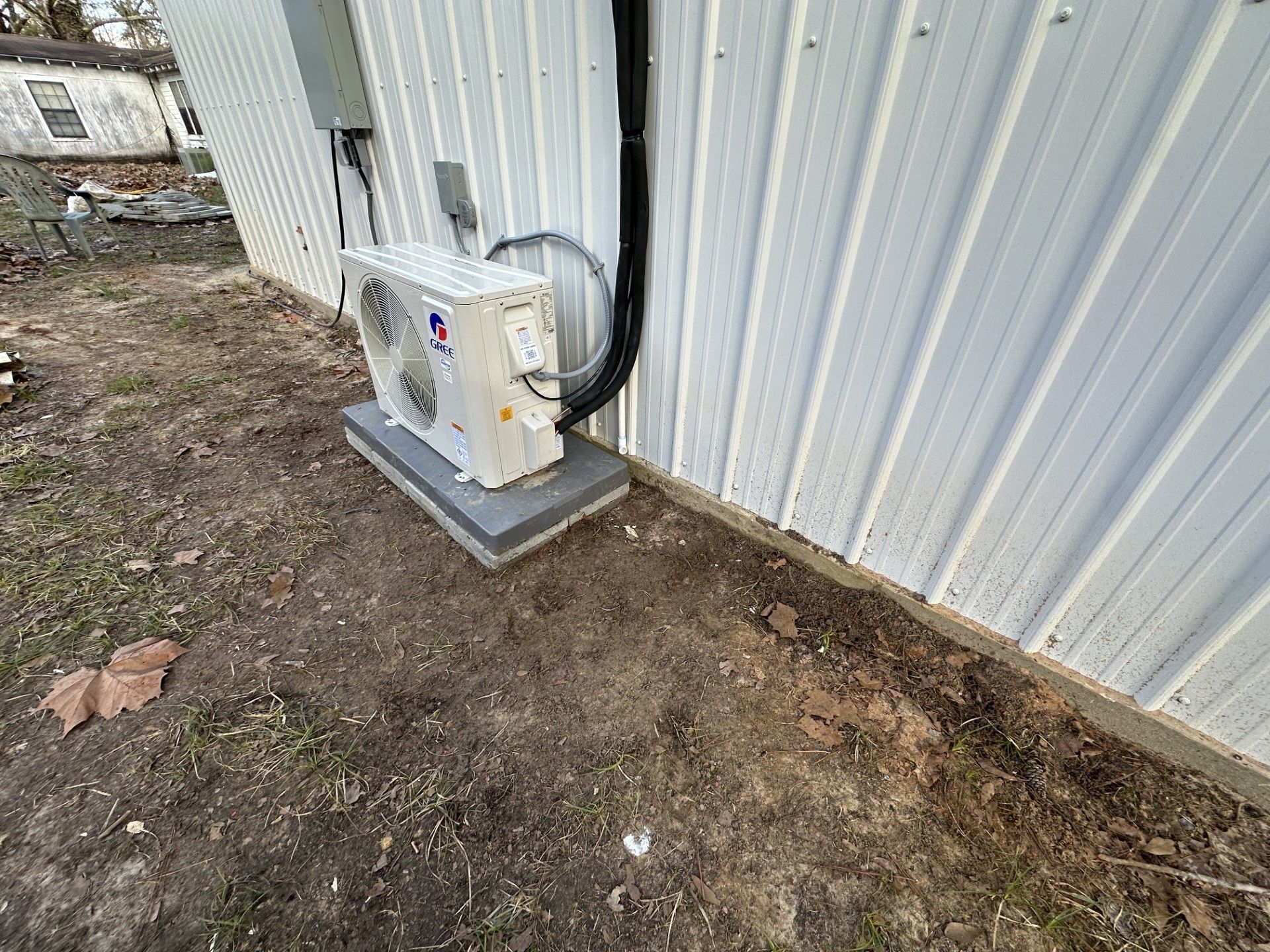 Outdoor electrical unit mounted on a metal building beside a gravel and dirt area