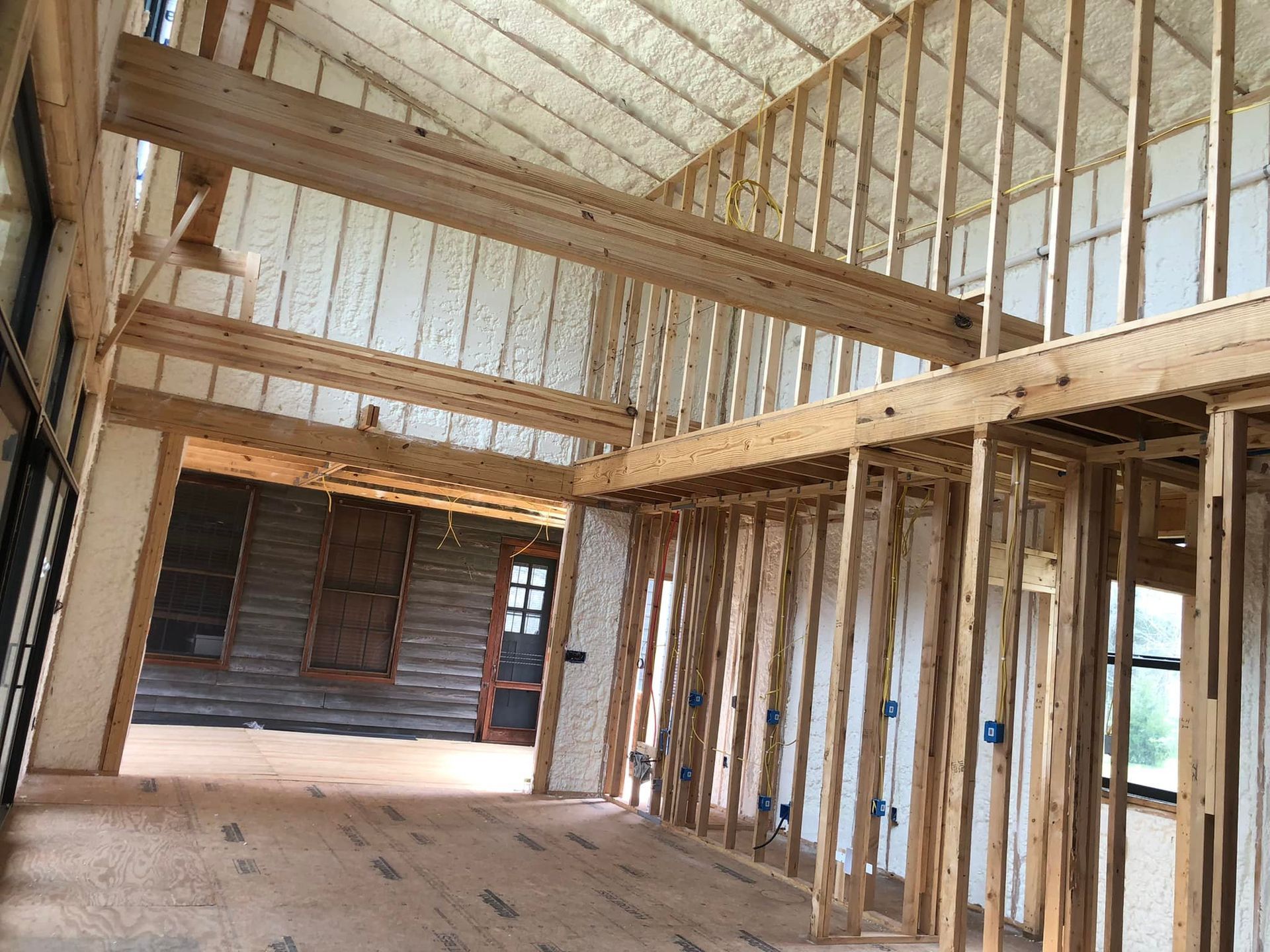 Interior of a house under construction; wooden frame walls, exposed beams, and insulation.