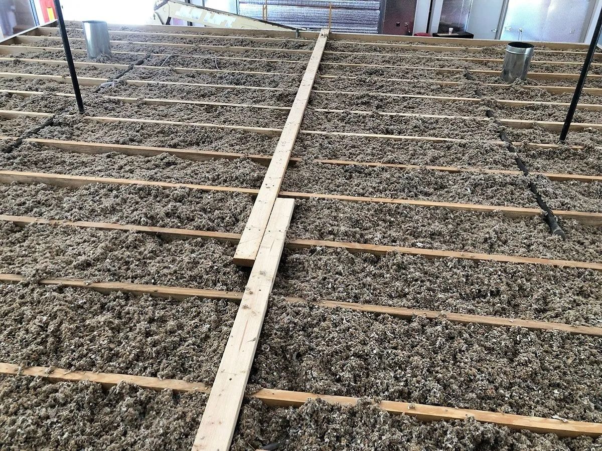 Overhead view of a roof under construction; insulation between wooden beams.