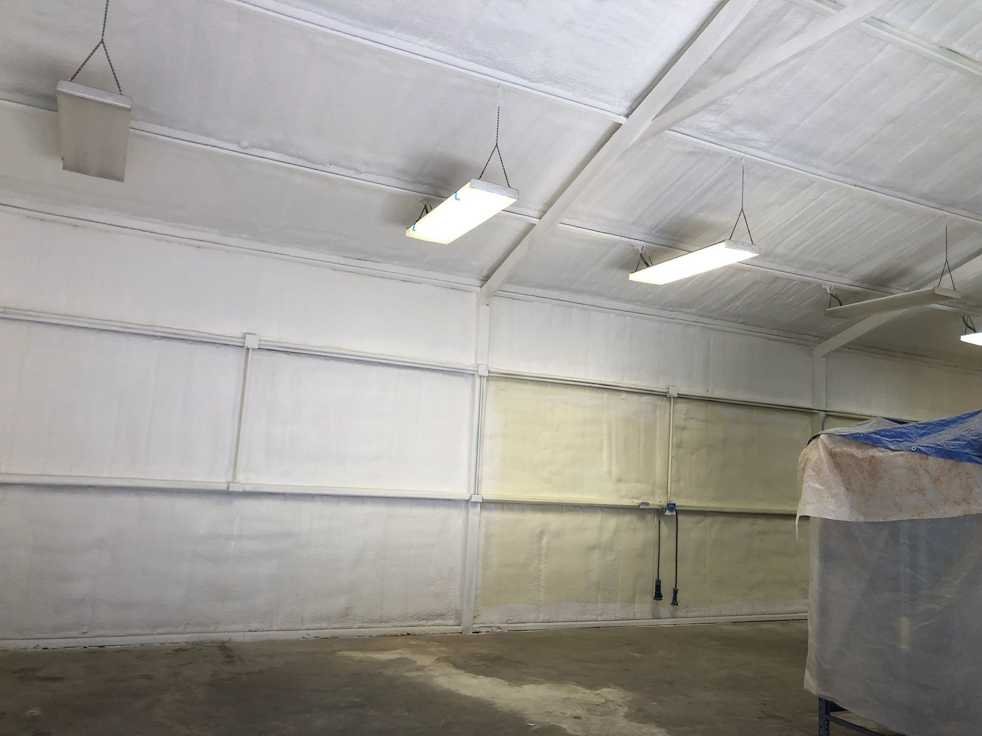 Interior of a white building with insulated walls and ceiling.  Overhead lights are visible.