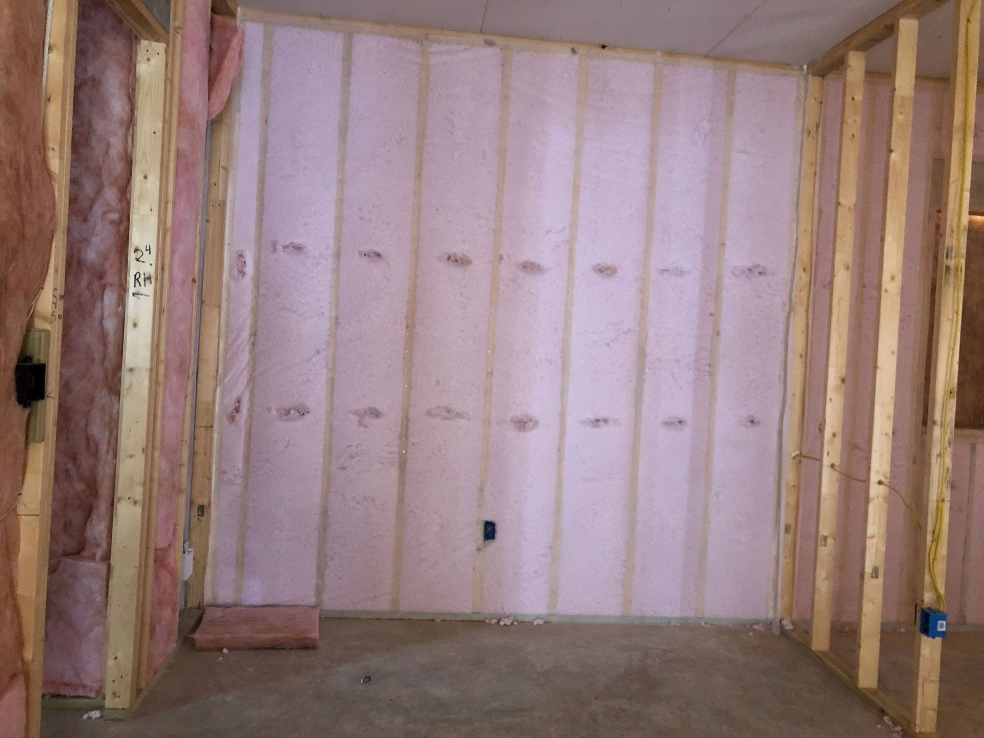 Interior wall under construction with pink insulation between wooden studs.