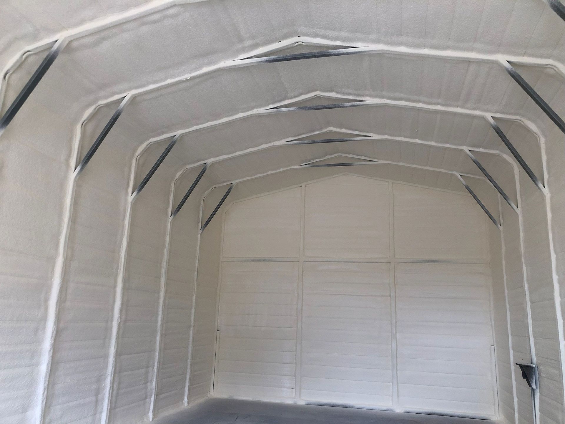 Interior of a white, arch-shaped building with metal frame supports and light gray walls.