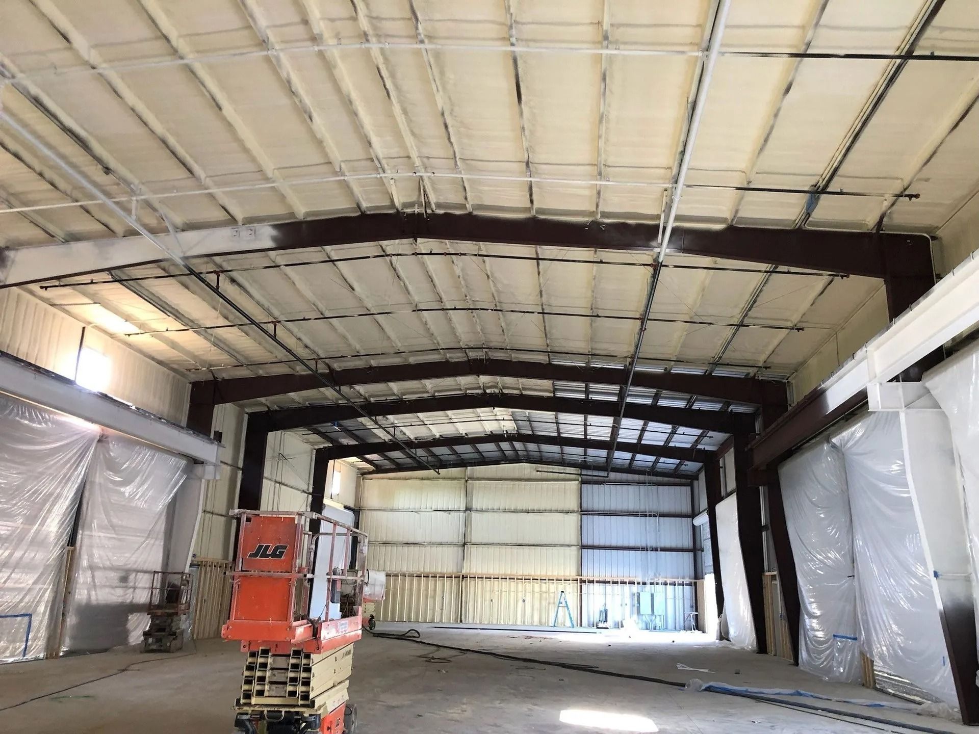 Interior view of a building under construction, spray foam insulation on walls and ceiling.