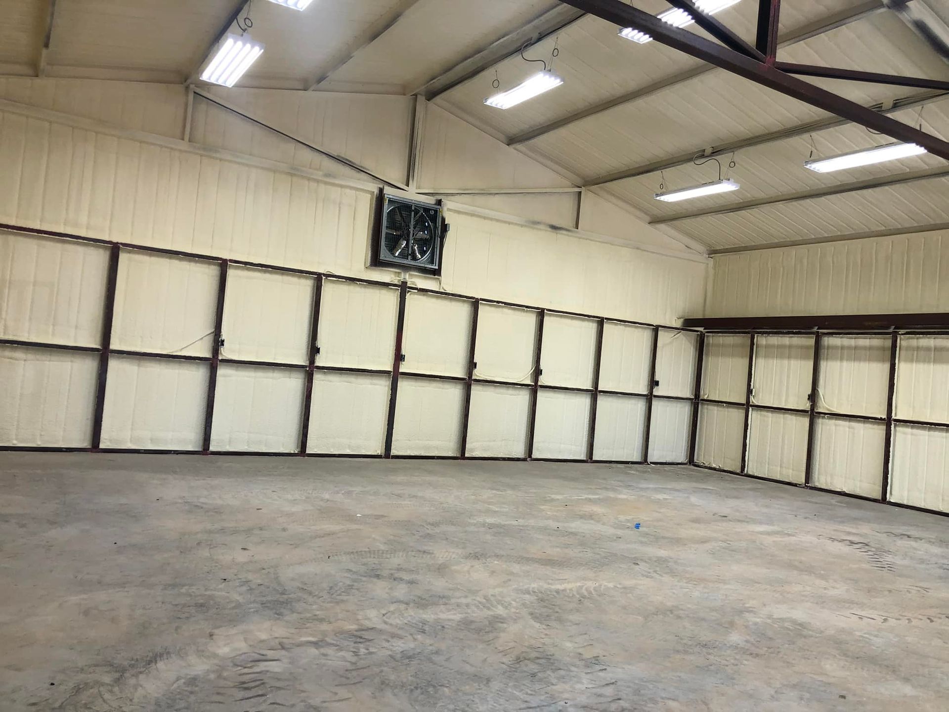 Interior view of a large warehouse space with spray foam insulation on the walls and ceiling.