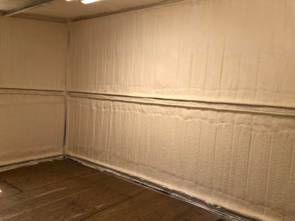 Interior of a room with spray foam insulation on the walls. The floor is wooden.