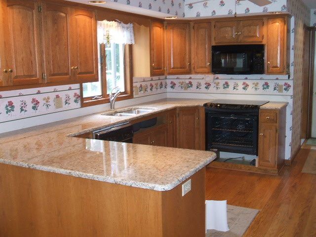 A kitchen with wooden cabinets and granite counter tops.