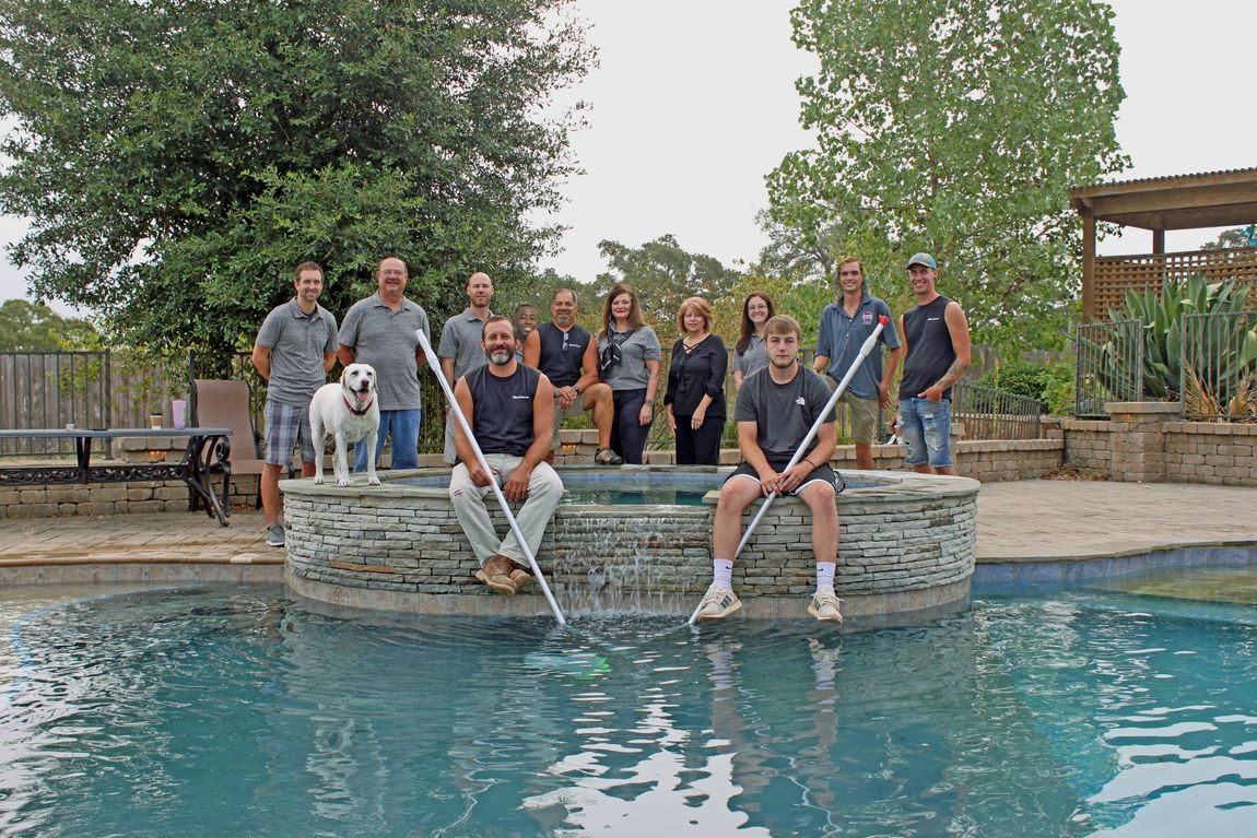 A group of people are posing for a picture in front of a swimming pool.