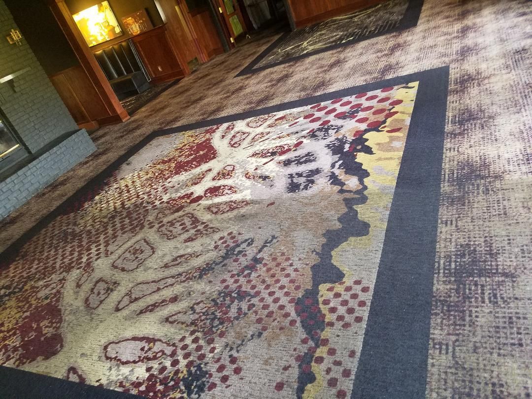 Large patterned rug on a polished lobby floor with warm lights and seating in the background