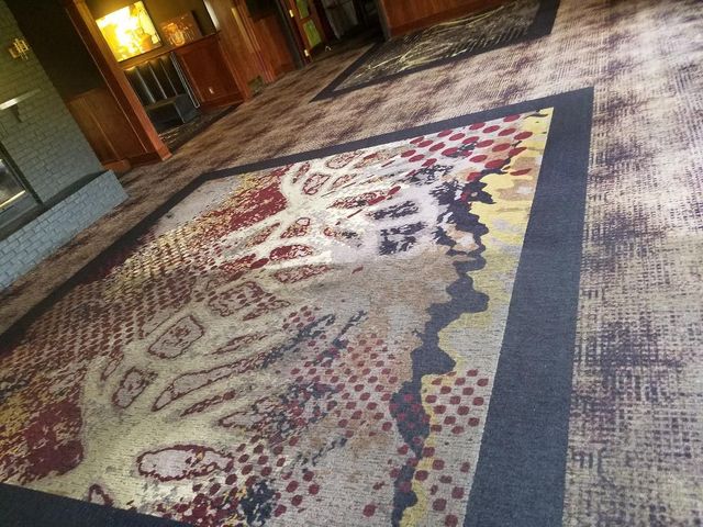 Large patterned rug on a polished lobby floor with warm lights and seating in the background