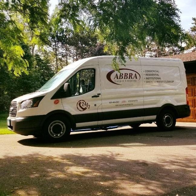 White ABBRA delivery van parked on a tree-lined road in sunlight