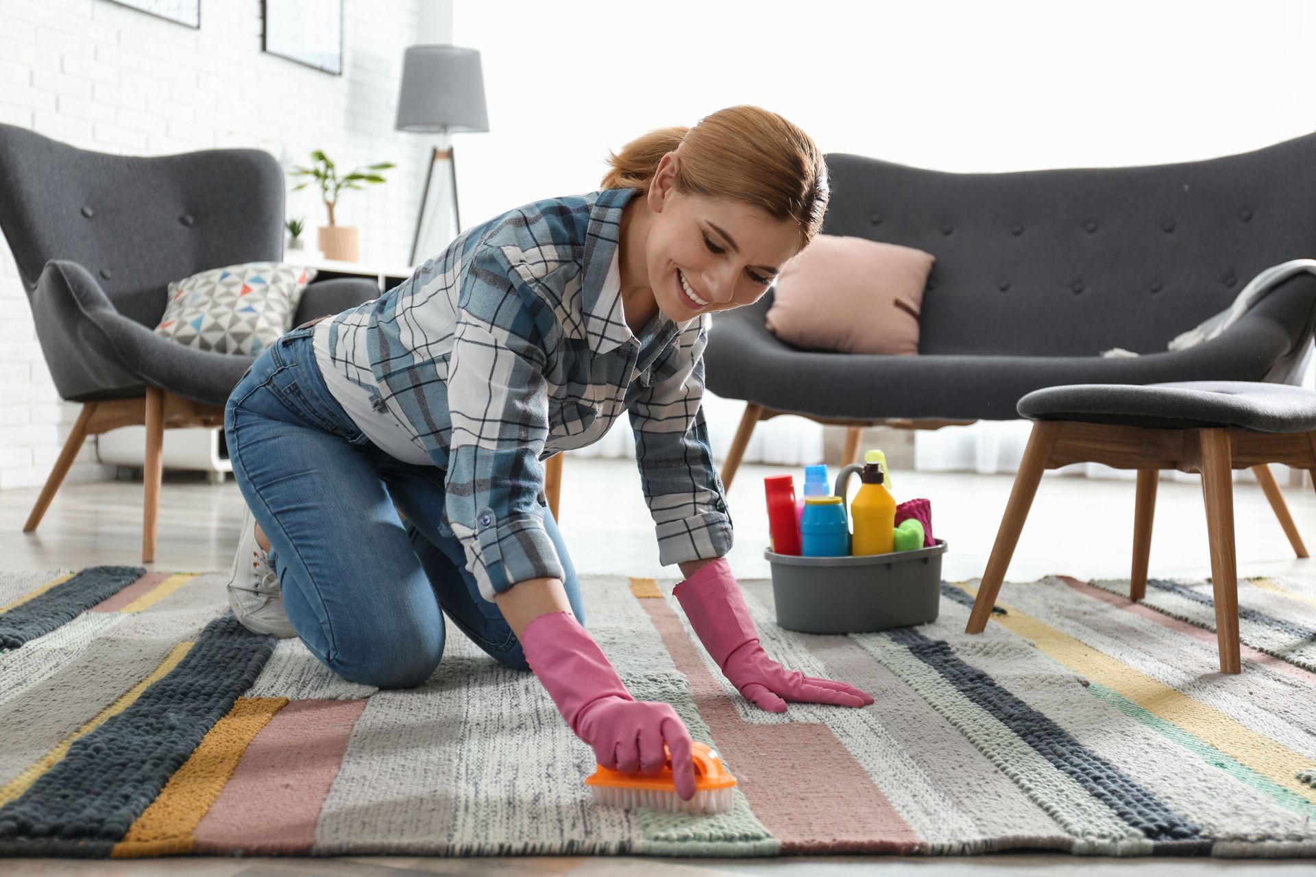 Woman kneeling on a rug, cleaning the floor with a sponge in a bright living room.
