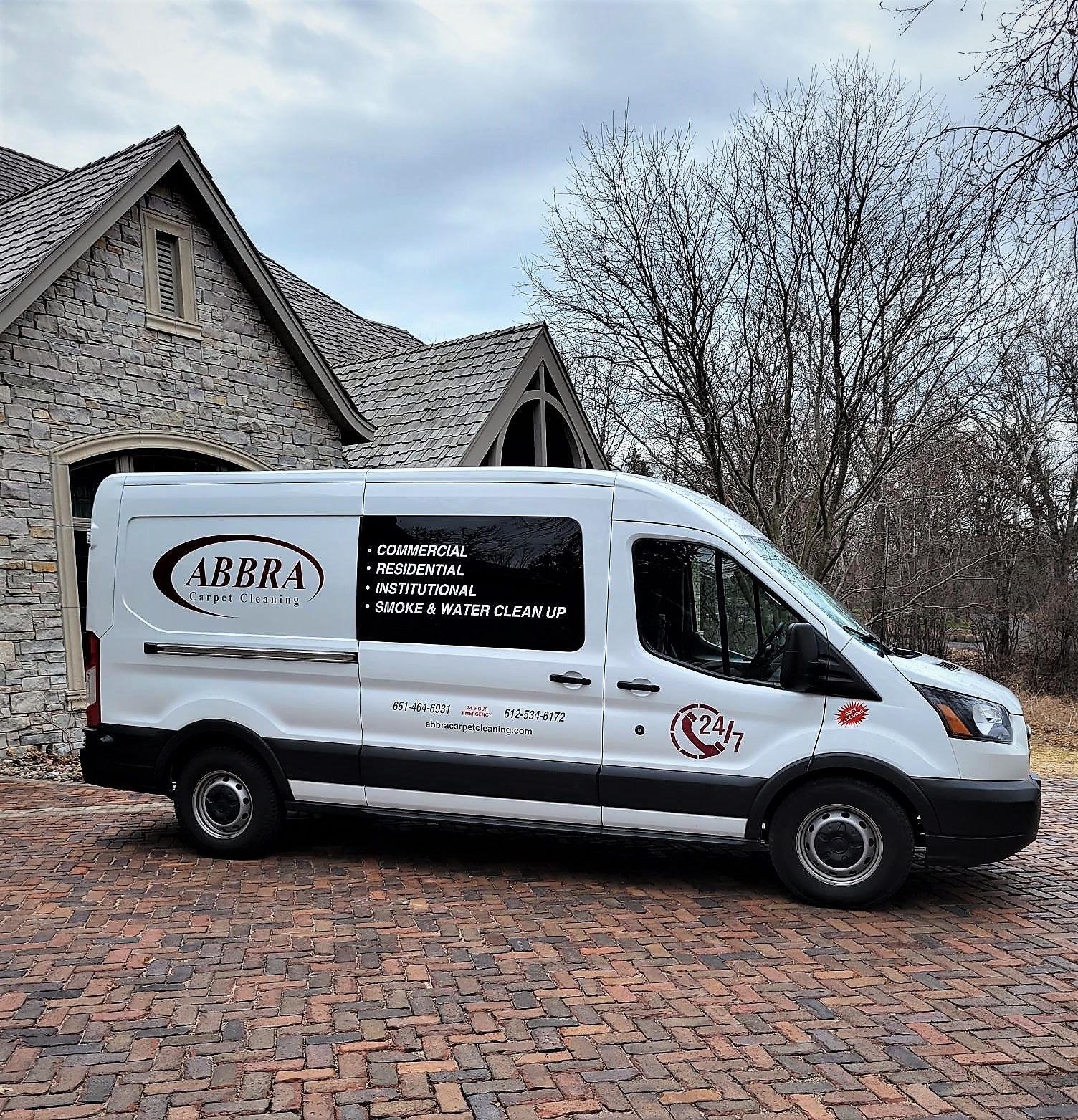 White service van parked on a cobblestone driveway in front of a stone house