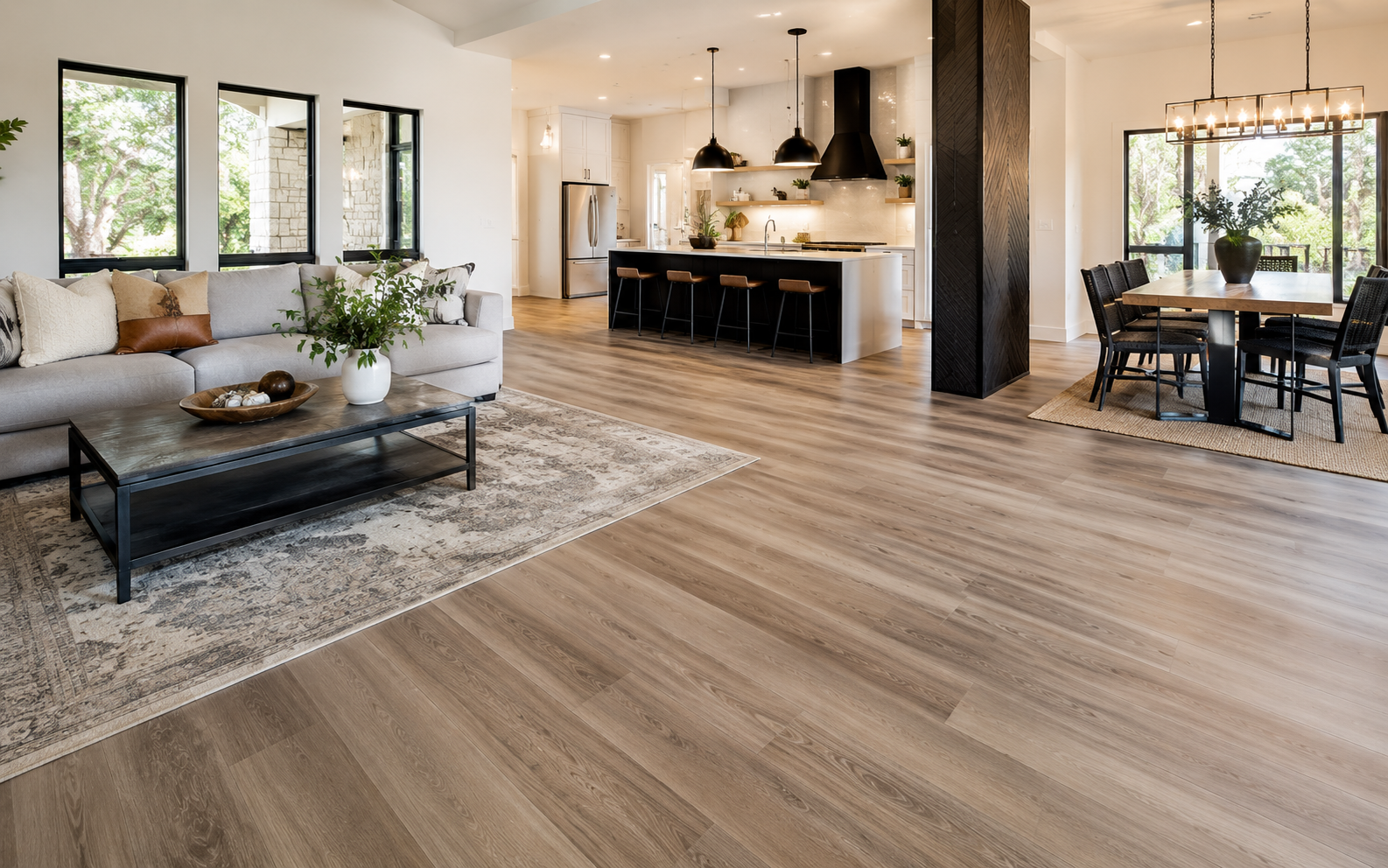 Modern open-plan living room and kitchen with wood floors, large windows, and black dining set