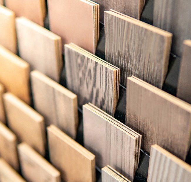 Wooden flooring samples arranged on a display rack, showing various wood grain patterns and colors.