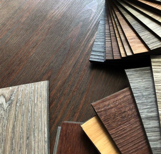 Flooring samples arranged on dark wood surface, displaying various wood grain patterns and colors.