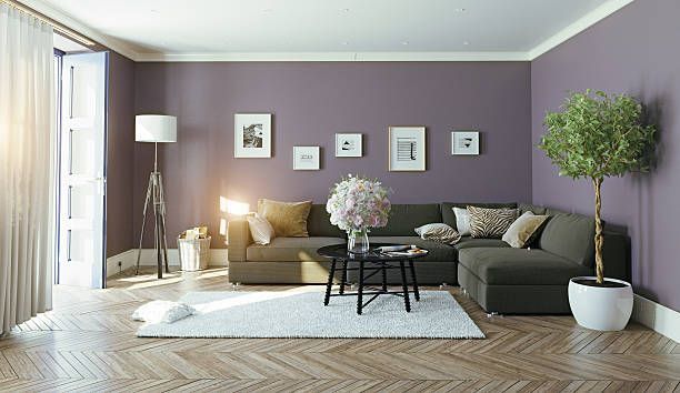 Living room with purple walls, sectional sofa, round coffee table, framed art, and a floor lamp.