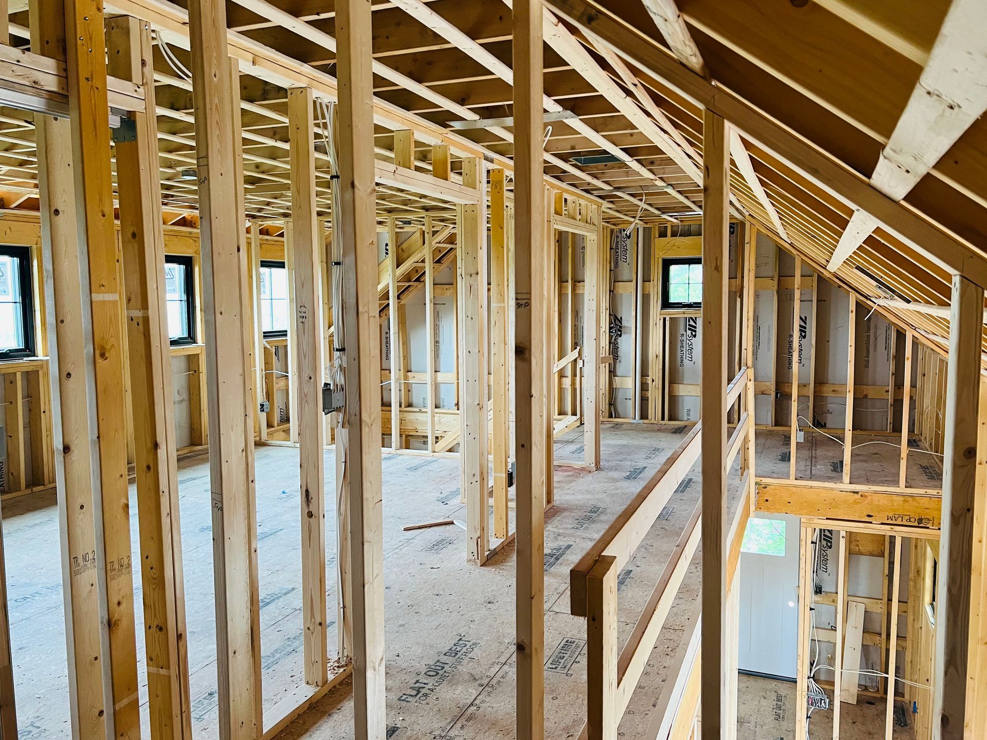 Interior view of a building under construction, showing wooden framing and exposed structure.