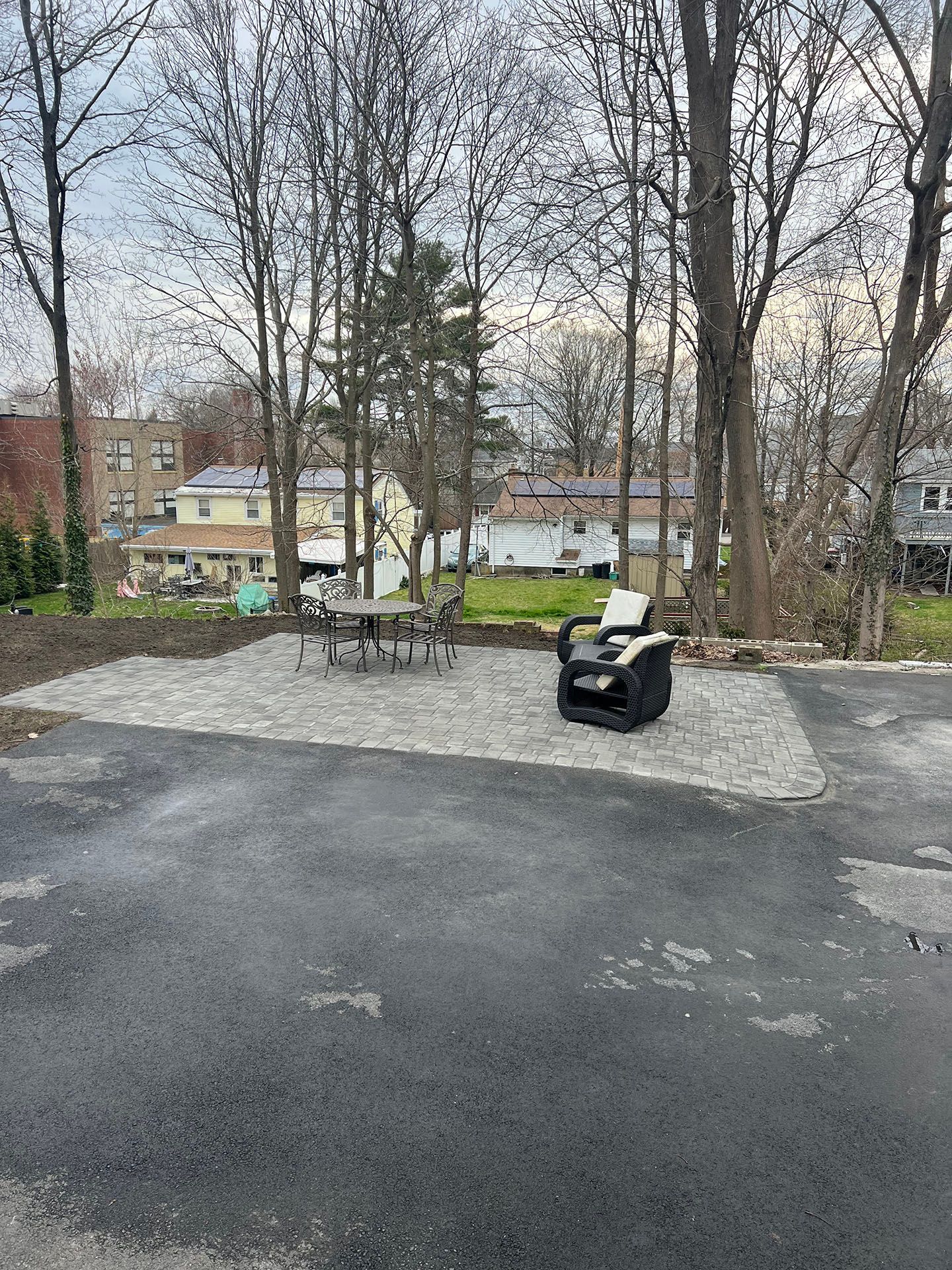 A patio with outdoor furniture, trees, and buildings in the background.