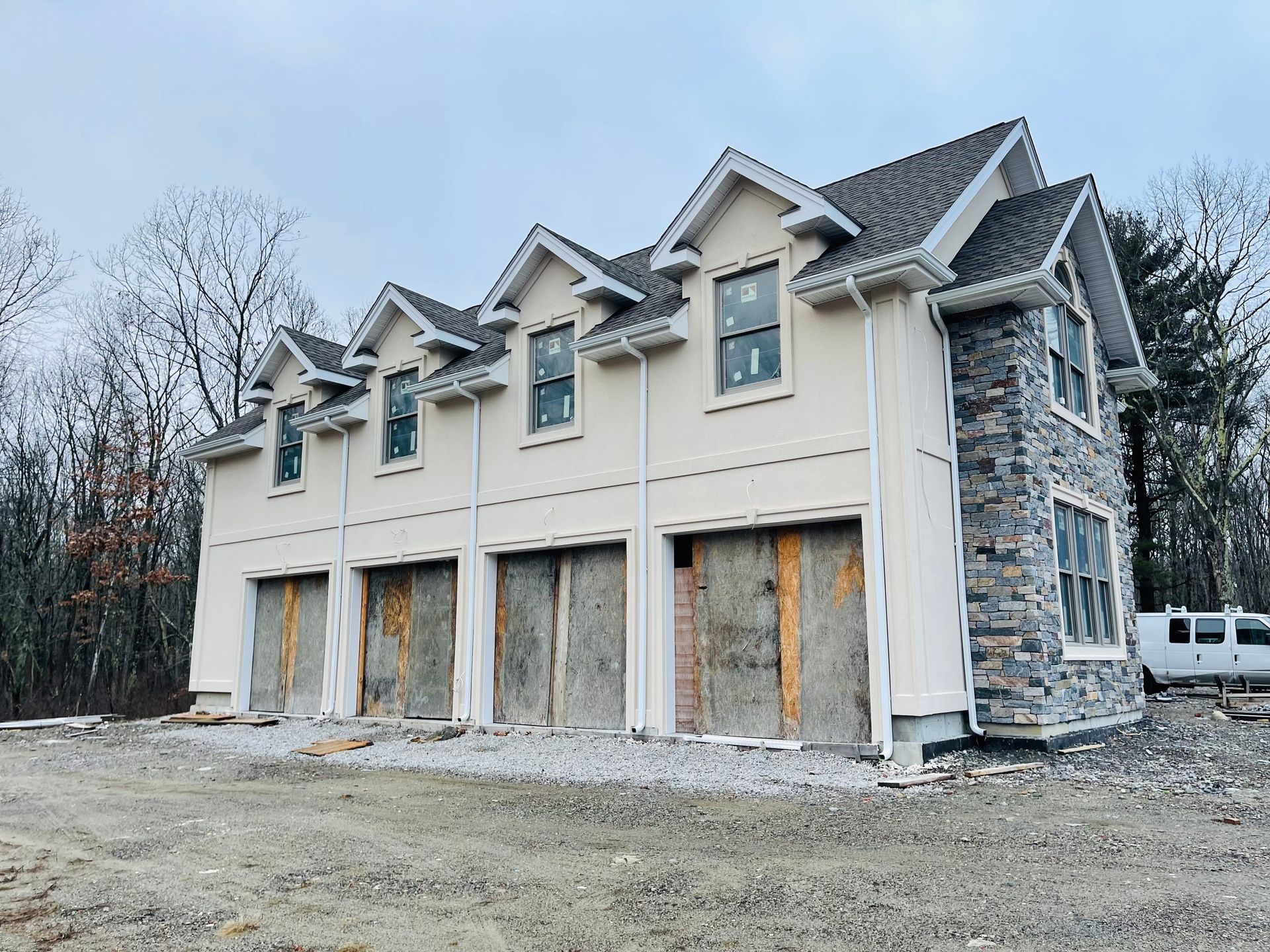 Garage under construction with four bays, tan stucco, and stone accents.