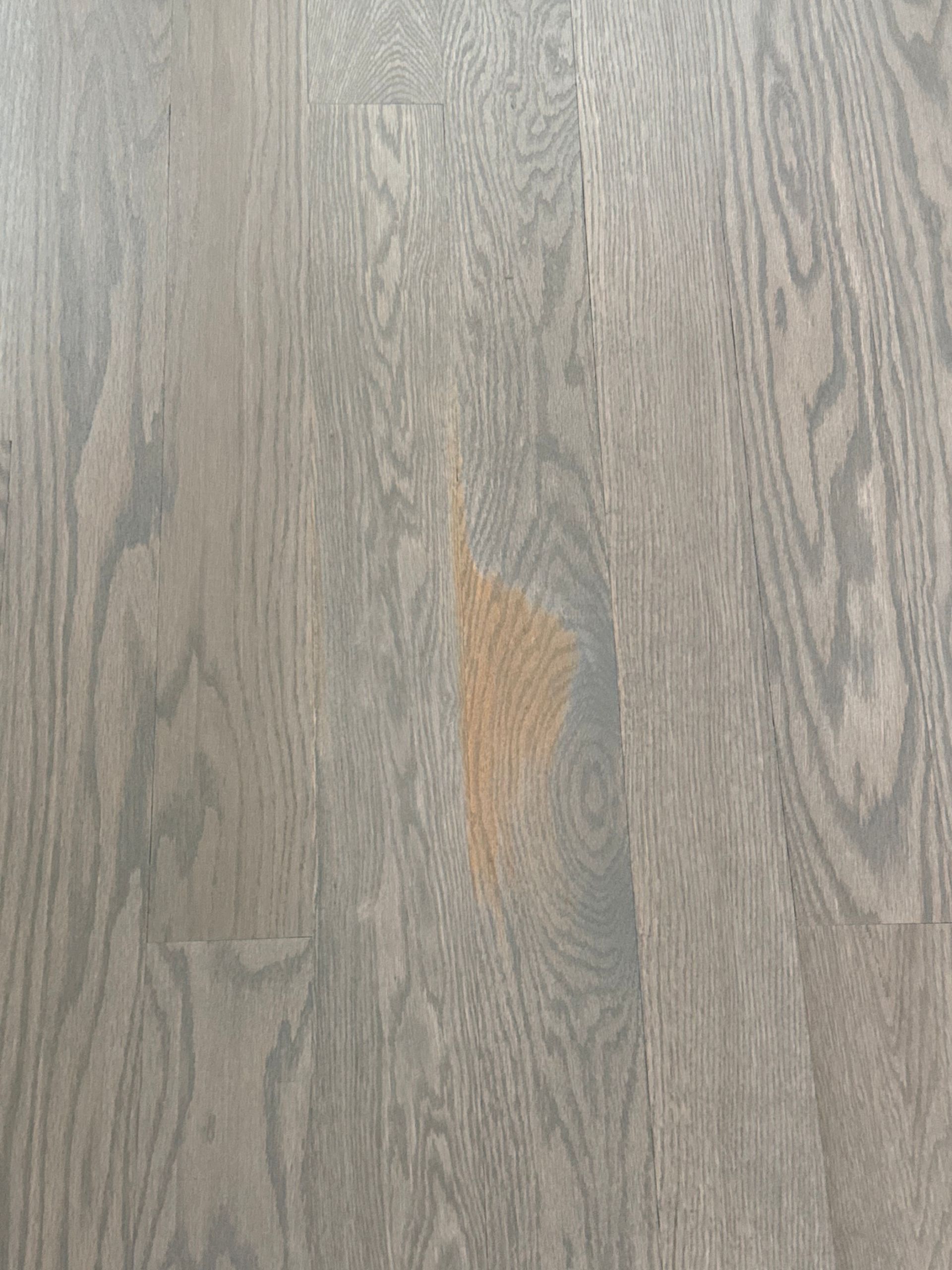 Gray-stained wooden floor with a large, orange stain in the center.