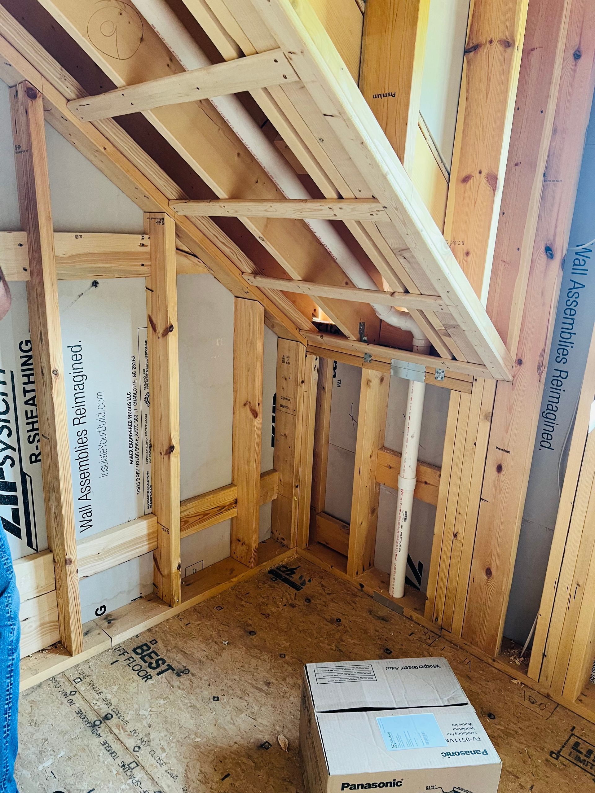 Framing of an angled interior wall and ceiling in a construction site.
