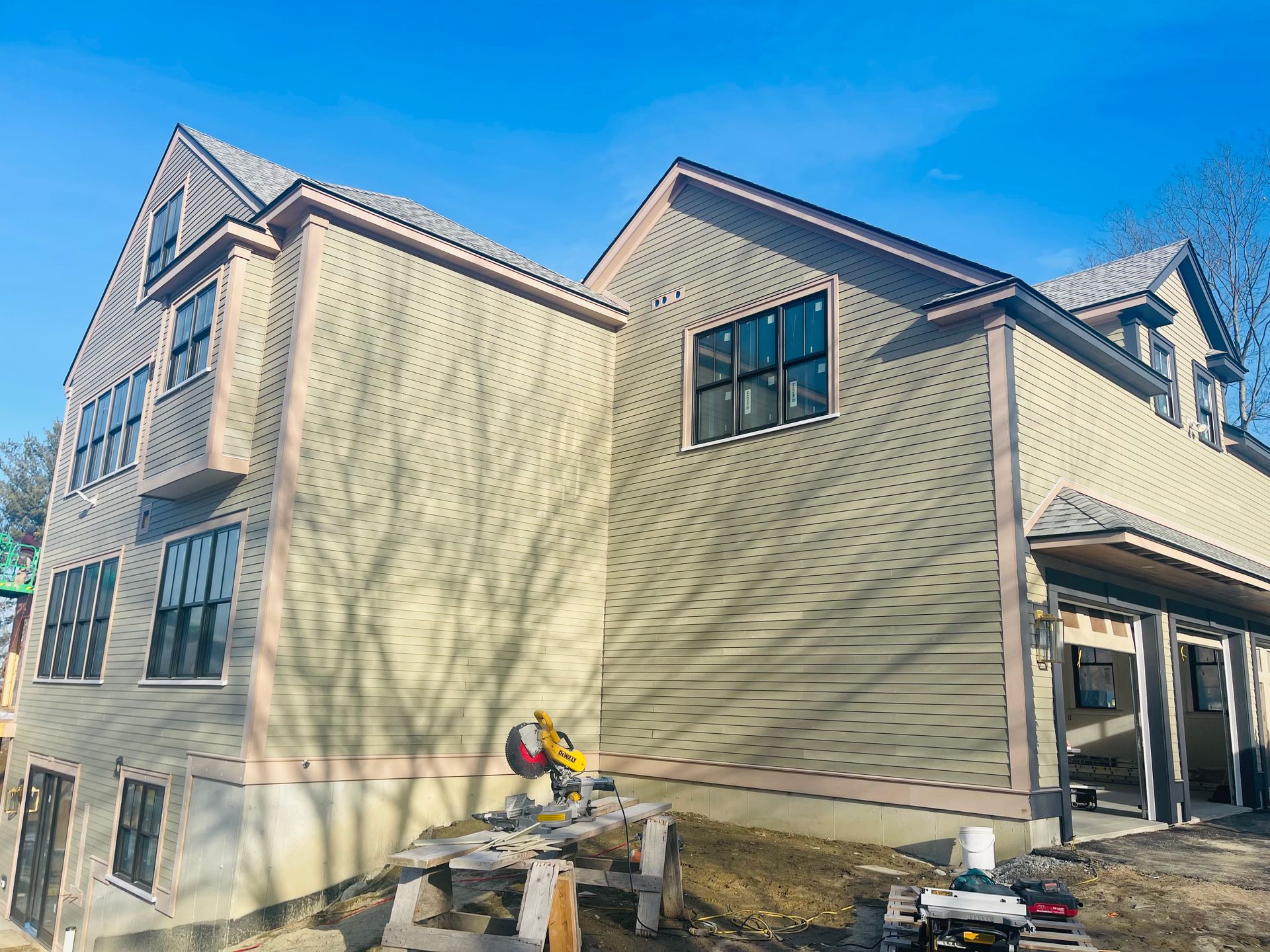 New construction home with light green siding and dark trim. Garage doors are visible.