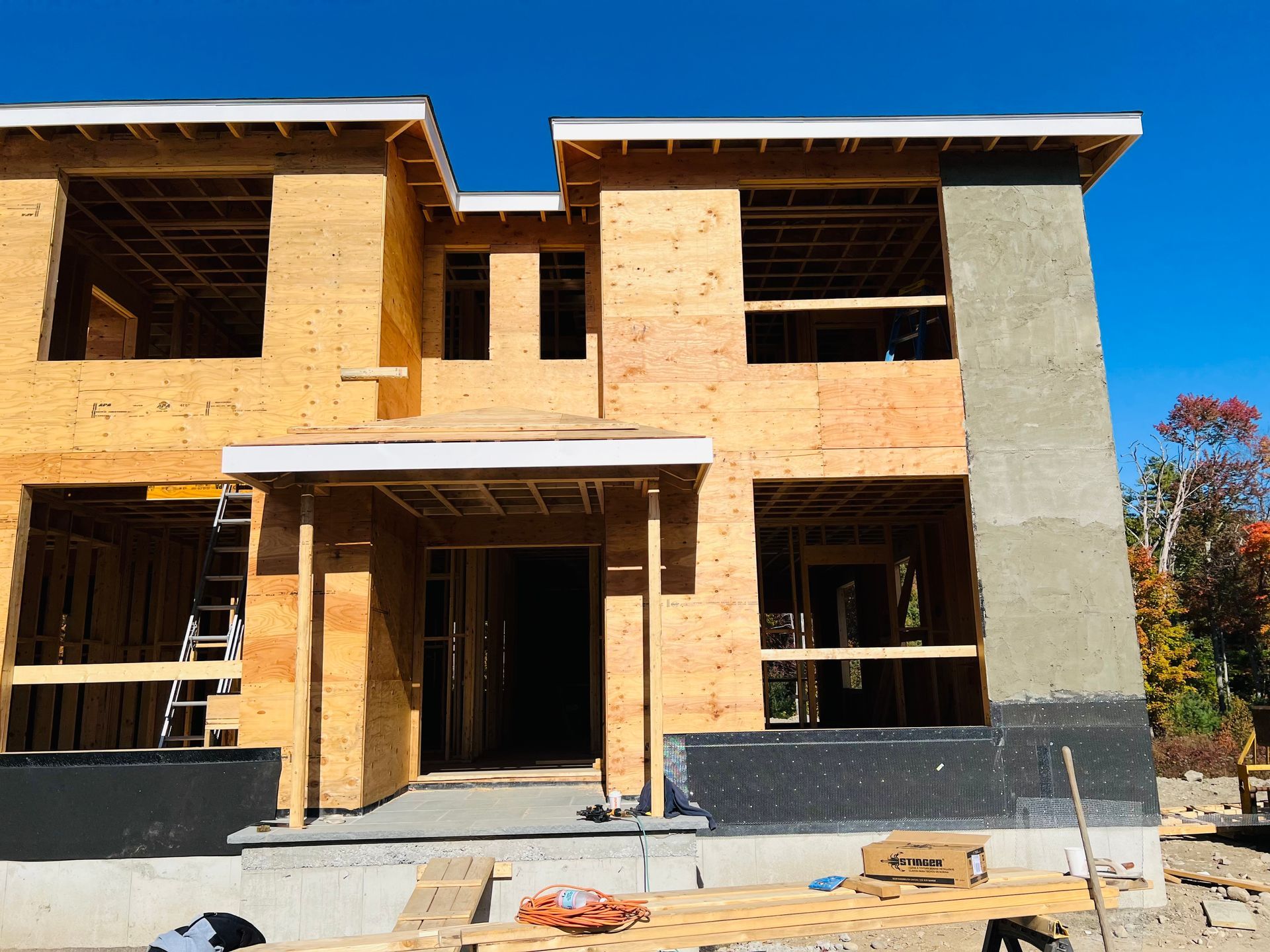 Construction of a two-story house. Wooden frame with unfinished walls, blue sky in background.