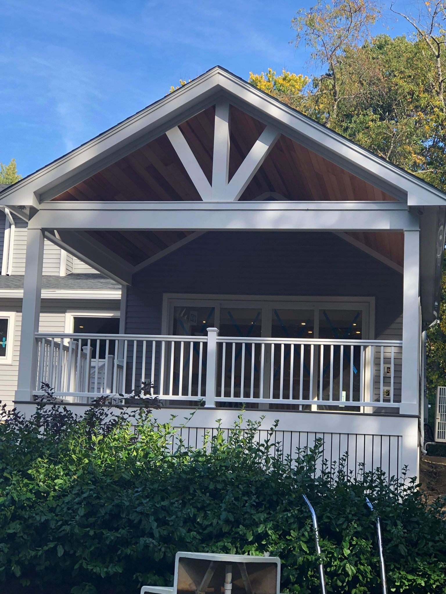 Covered porch with white railings, gray walls, and exposed wood beams.