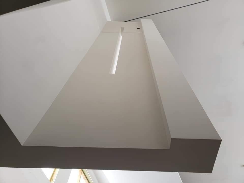 A white ceiling with a recessed light fixture and a downward-facing rectangular beam.