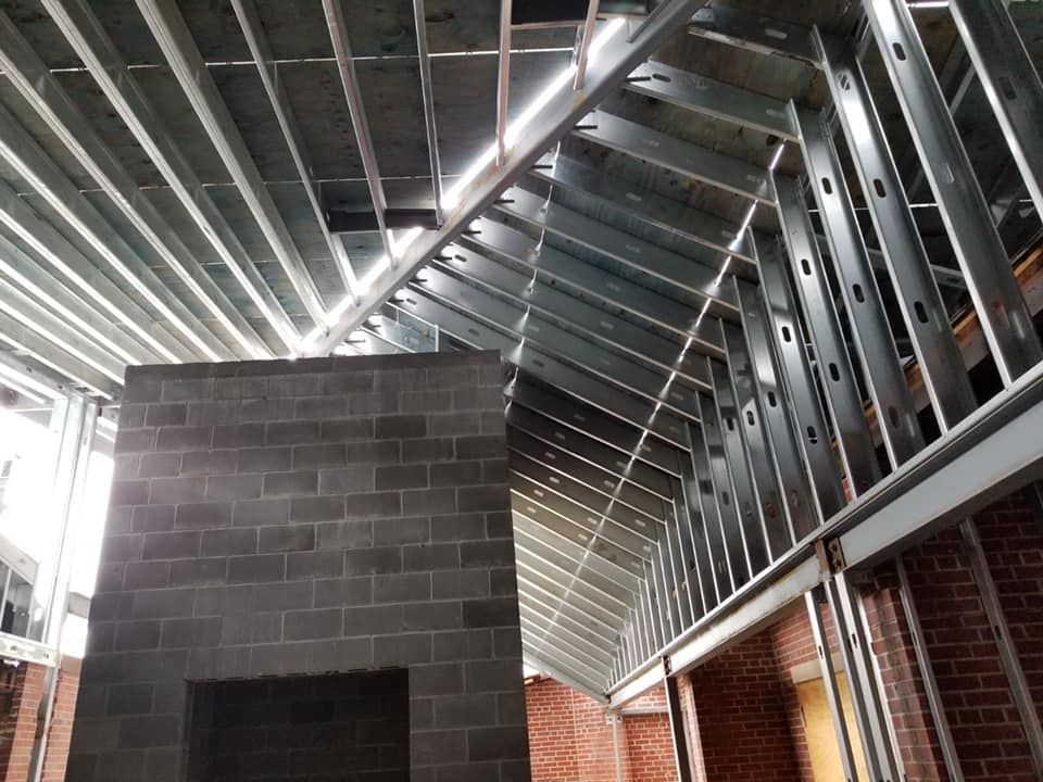 Steel framing and brick walls under construction; view includes a fireplace and angled ceiling.