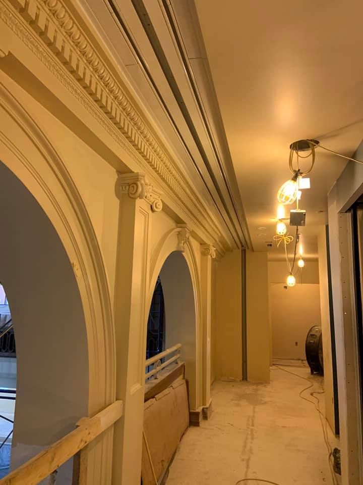 Hallway with ornate archways and exposed ceiling, warm lighting, and construction materials.