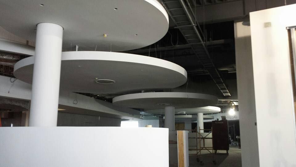 White circular ceiling panels suspended from the ceiling, supported by white columns, in a construction setting.