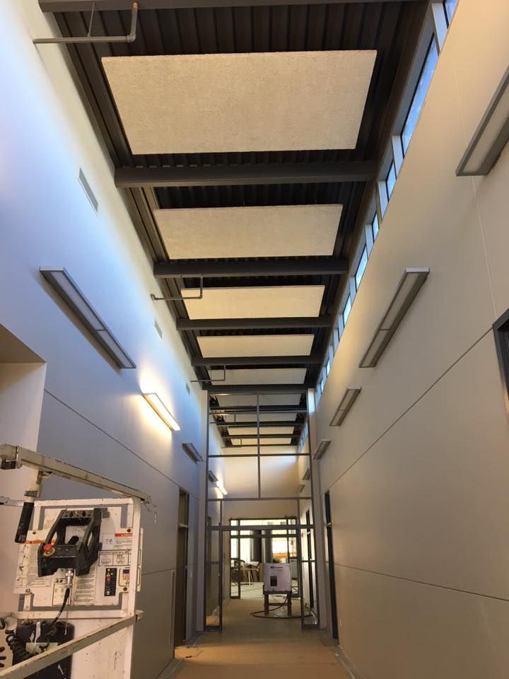 Narrow hallway with white walls, ceiling panels, and glass doors at the end.