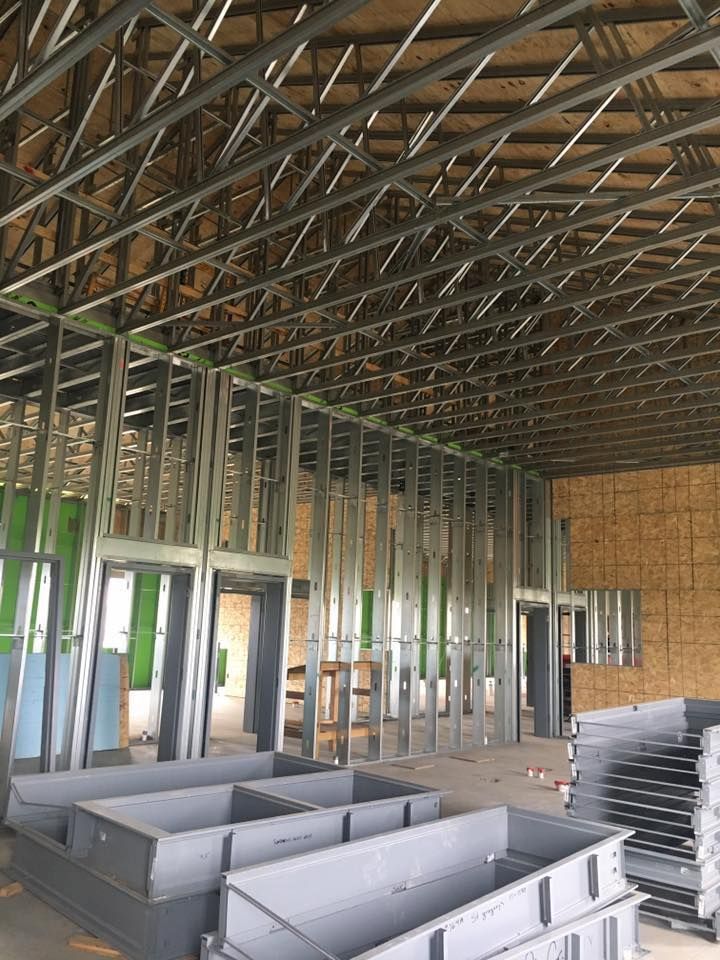 Interior construction with metal framing. Open space with walls, ceiling, and stacked metal components.