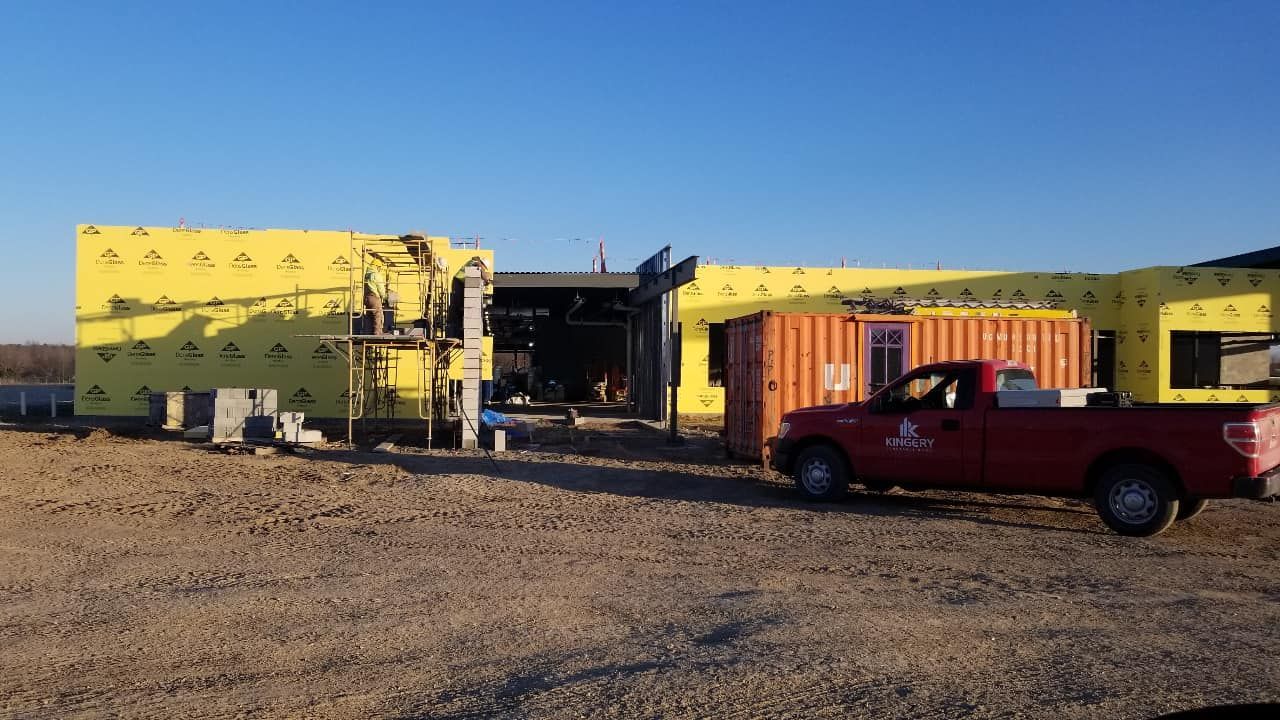 Construction site with yellow insulated walls, a red truck, and a shipping container.
