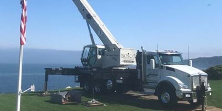 A truck with a crane on top of it is parked next to a flag