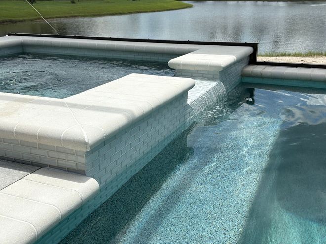 Blue swimming pool with white built-in seating and a spa section beside a grassy lawn