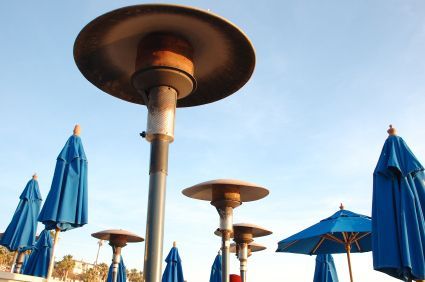 Blue patio umbrellas around outdoor heaters against a clear sky