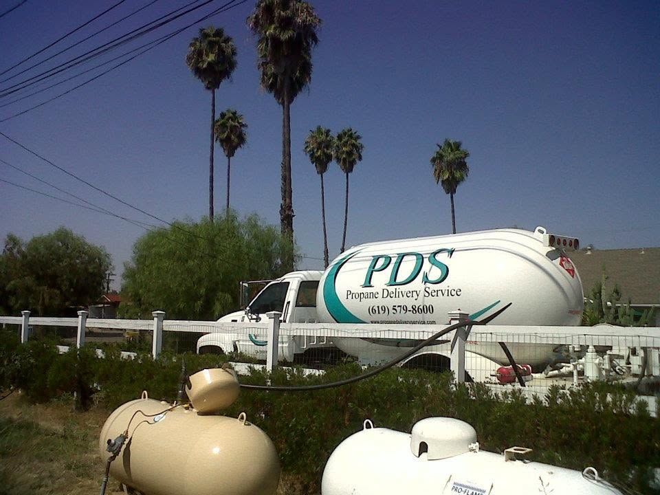 PDS propane delivery tank on a truck in a sunny yard with palm trees and storage tanks