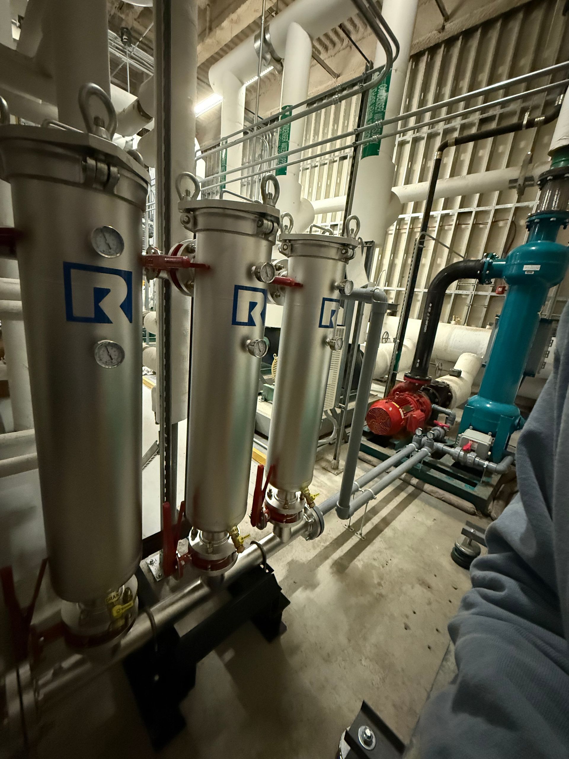 A person is standing in a room with a lot of pipes.