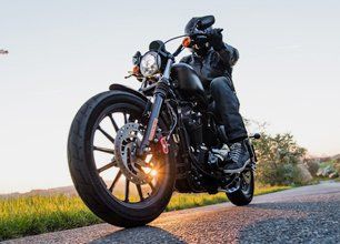 Man sat on motorcycle on the road during sunrise