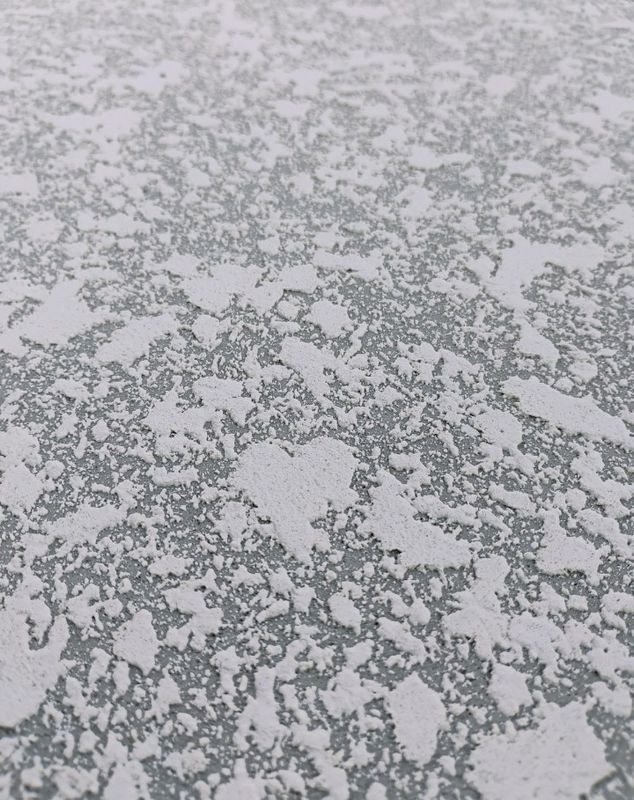 Gray, speckled icy surface with irregular white patches and cracks