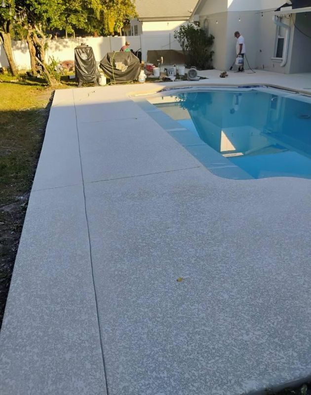Backyard swimming pool with a concrete deck and covered lounge chairs in warm sunlight
