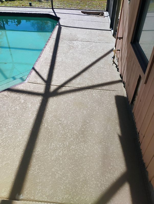 Poolside concrete patio beside a turquoise swimming pool, with long diagonal shadows and a house wall.