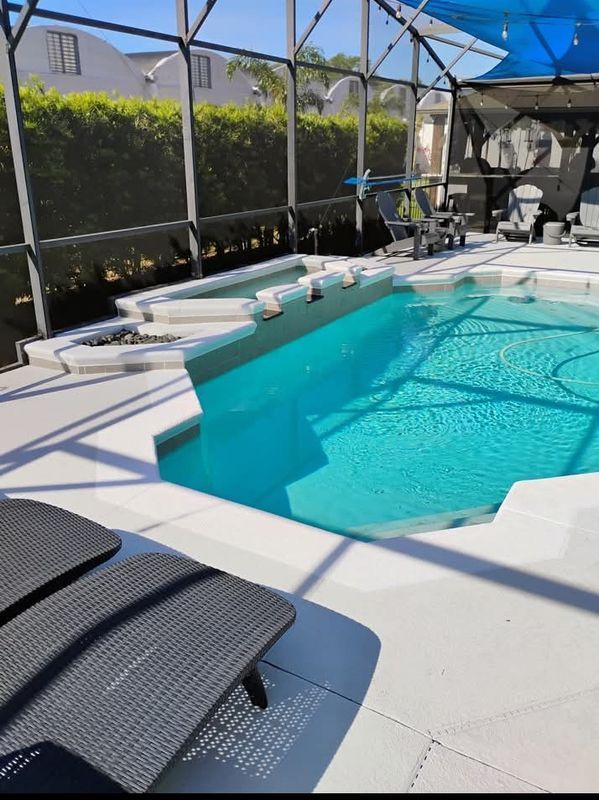 Backyard screened-in pool with turquoise water, white deck, and lounge chairs under a blue canopy