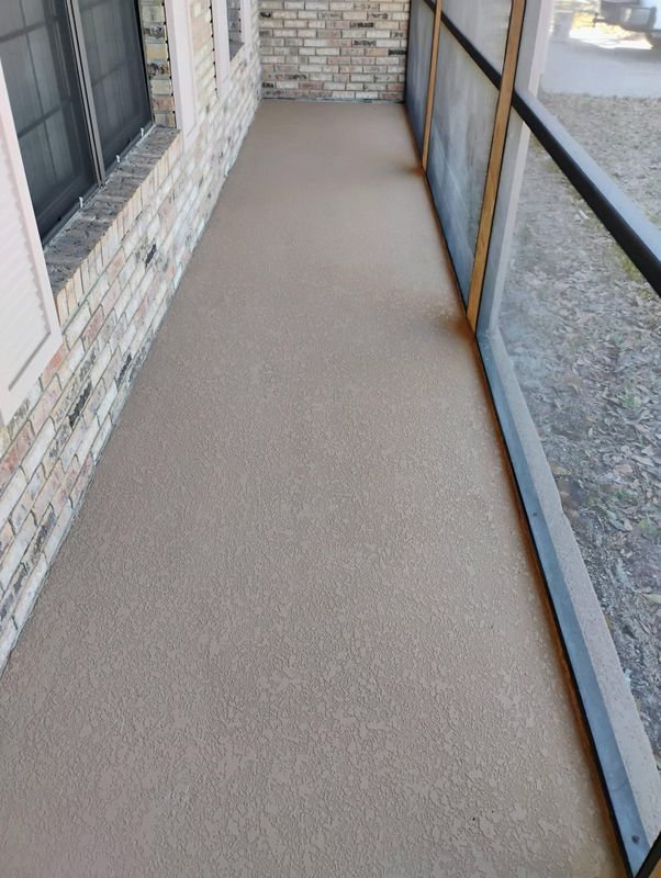 Narrow covered outdoor walkway with brick wall, windows, and glass railing over gravel below