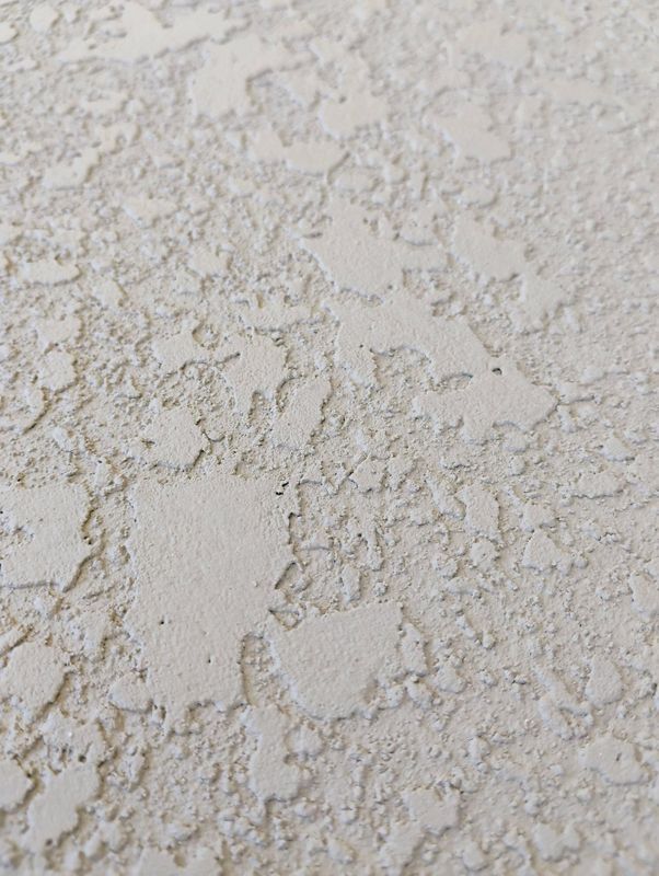 Close-up of a beige textured stucco wall with a rough, uneven surface.