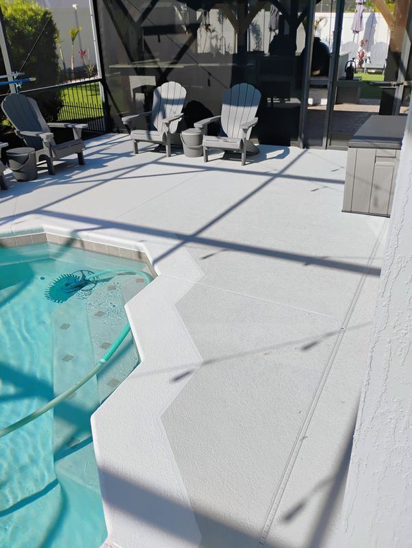 Poolside patio with turquoise pool, white chairs, and screened seating area in bright sunlight
