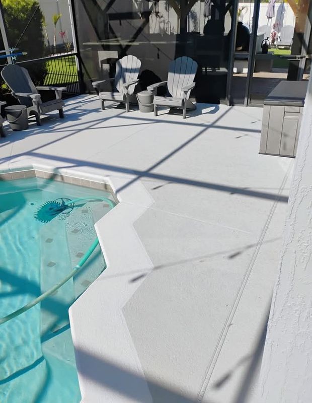 Poolside patio with white deck, turquoise pool, and lounge chairs in sunlight